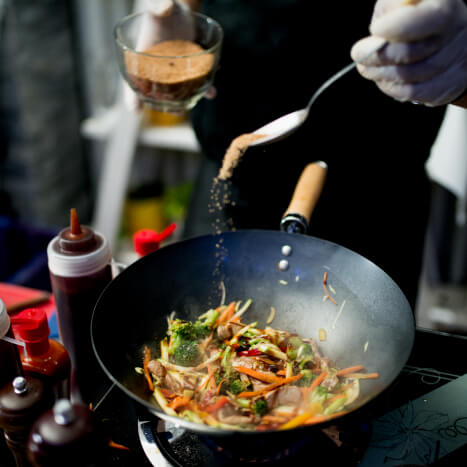 Professional chef adds spice to a steaming hot pan.