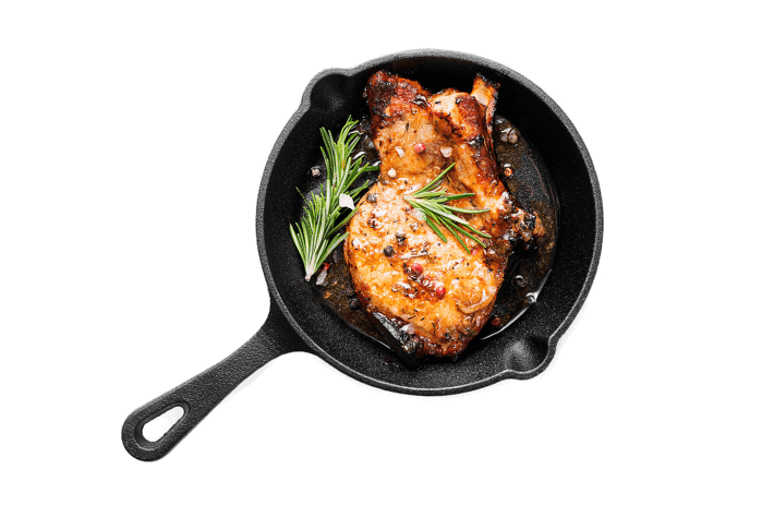 Fried pork steak in frying pan isolated on white background.